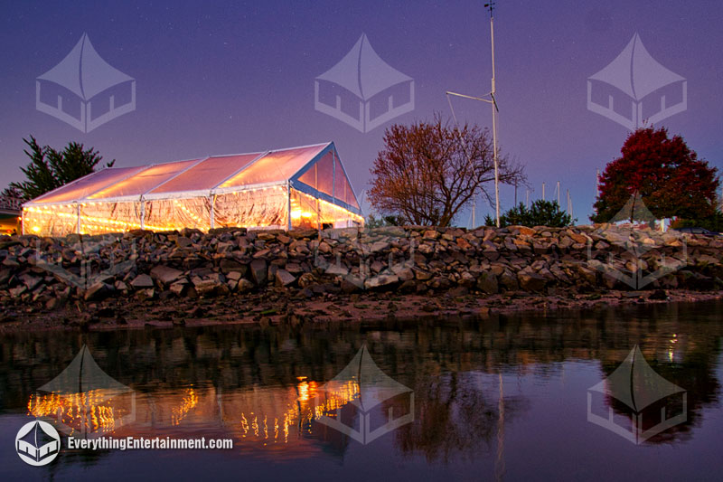Clear top wedding tent at night with reflection in the water