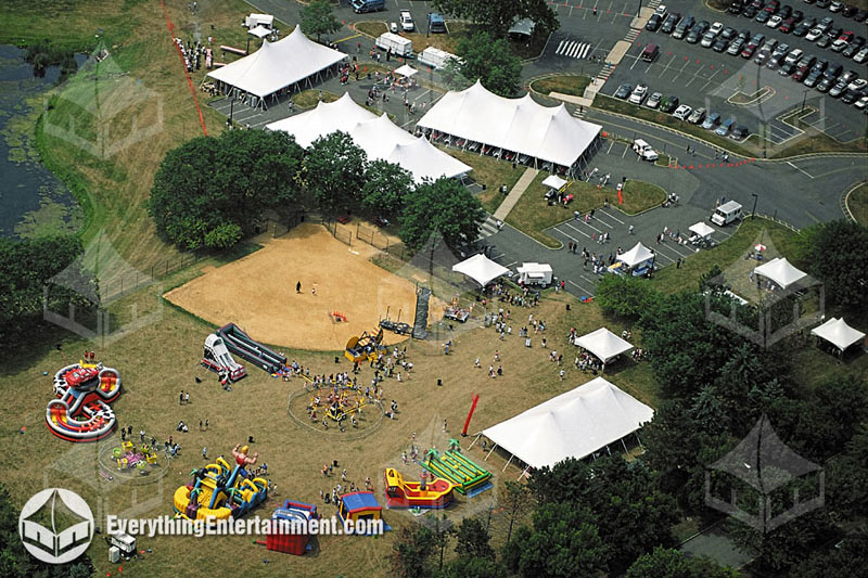 Multiple huge tension tents and amusements setup on large campus aerial view.