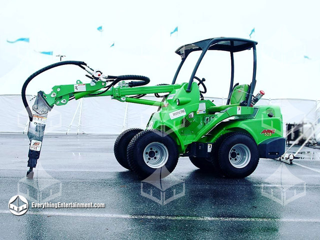 large green articulated loader on asphalt with a tent in the background