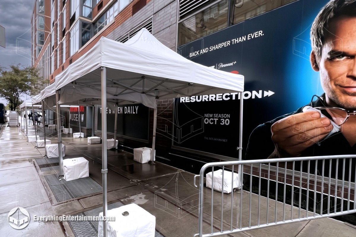 Row of white 10x10 pop-up canopy tents with weighted leg covers and crowd control barricades on a New York City sidewalk by Everything Entertainment.