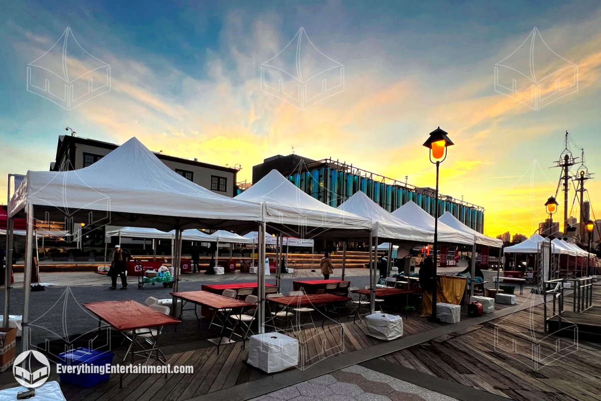 Row of 10x10 high-peak festival tents with set up tables and chairs along the Pier 17 boardwalk in Manhattan by Everything Entertainment