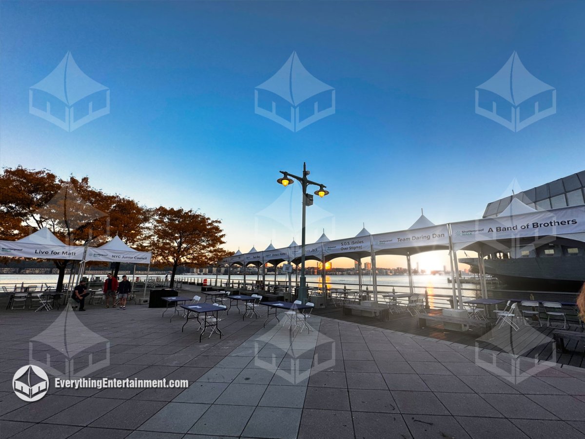 Row of 10x10 high-peak frame tents with team banners and registration tables ballasted on the Pier 84 plaza overlooking the Hudson River in NYC by Everything Entertainment.
