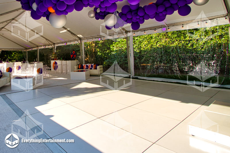 white dance floor setup inside tent with purple balloon decorations