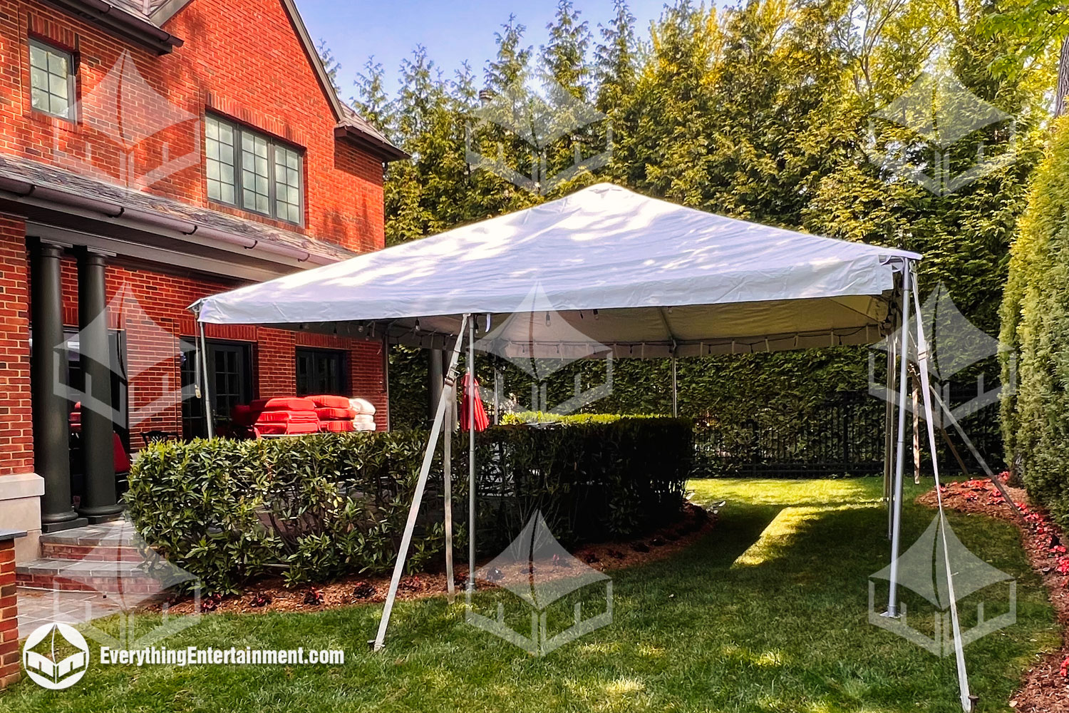 20x20 white top frame tent set up in backyard with greenery.
