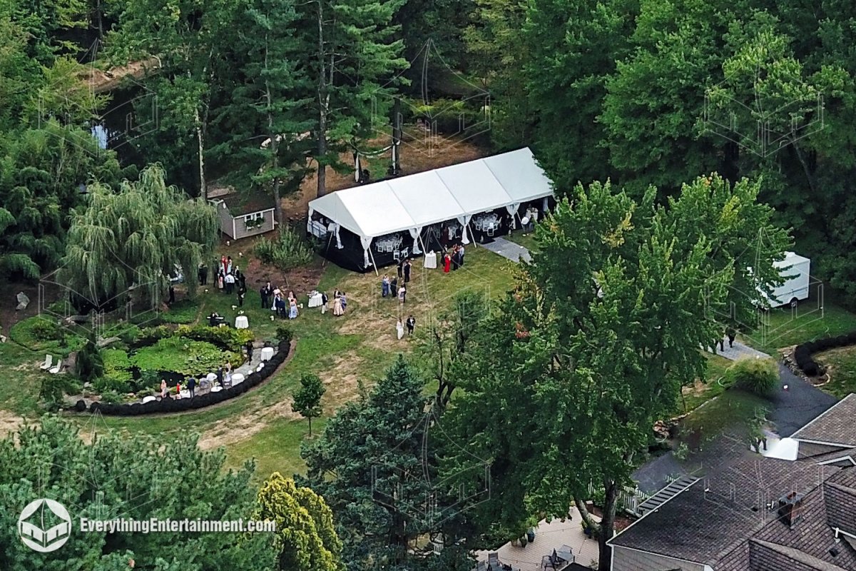 Aerial view of a 30x60 wedding tent setup on a custom elevated subfloor in a sloped backyard overlooking a private lake.