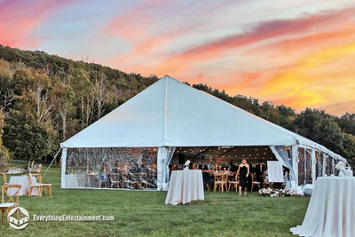 a 40x90 foot frame tent set up in a large field in Wallkill, NY at sunset