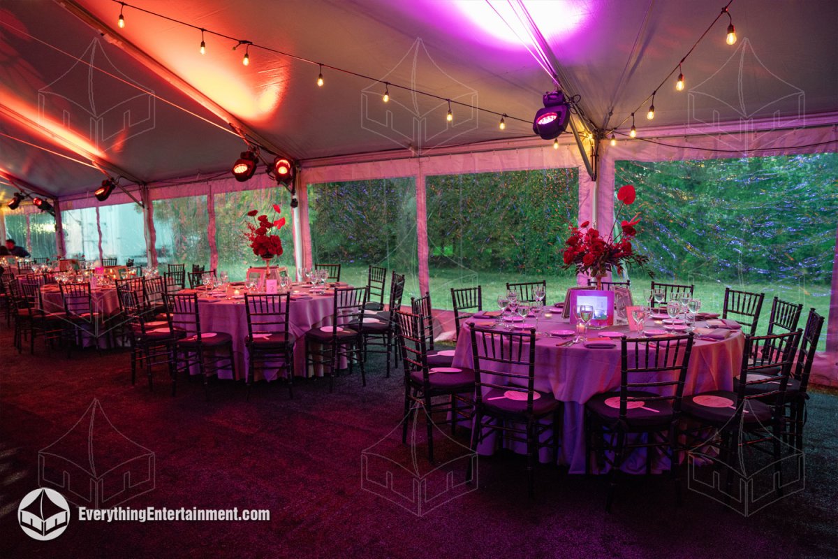 Round gala dining tables arranged along clear vinyl sidewalls in a 50x120 maxi frame tent overlooking the Snug Harbor grounds by Everything Entertainment.