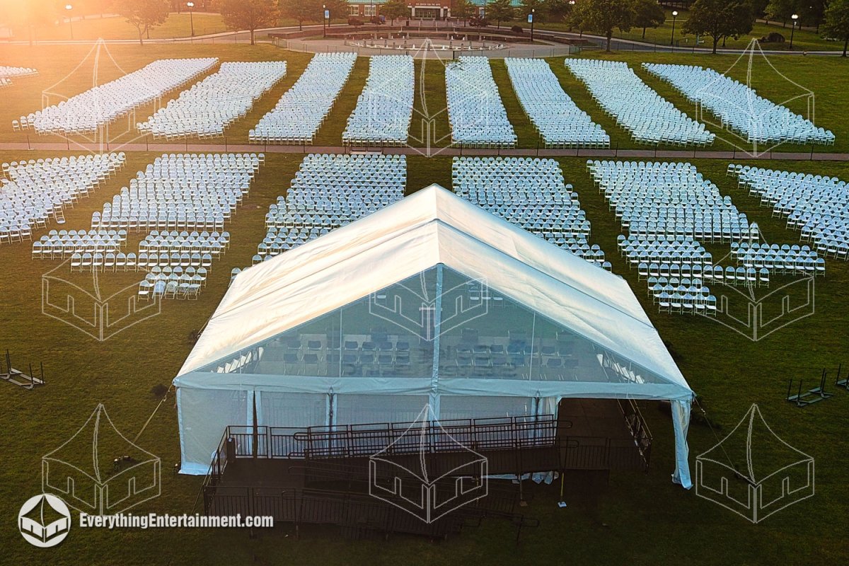 High-angle aerial view of a 50x30 open gable frame tent with an ADA ramp and 28x40 stage surrounded by 6,500 white folding chairs set up on a university lawn by Everything Entertainment.