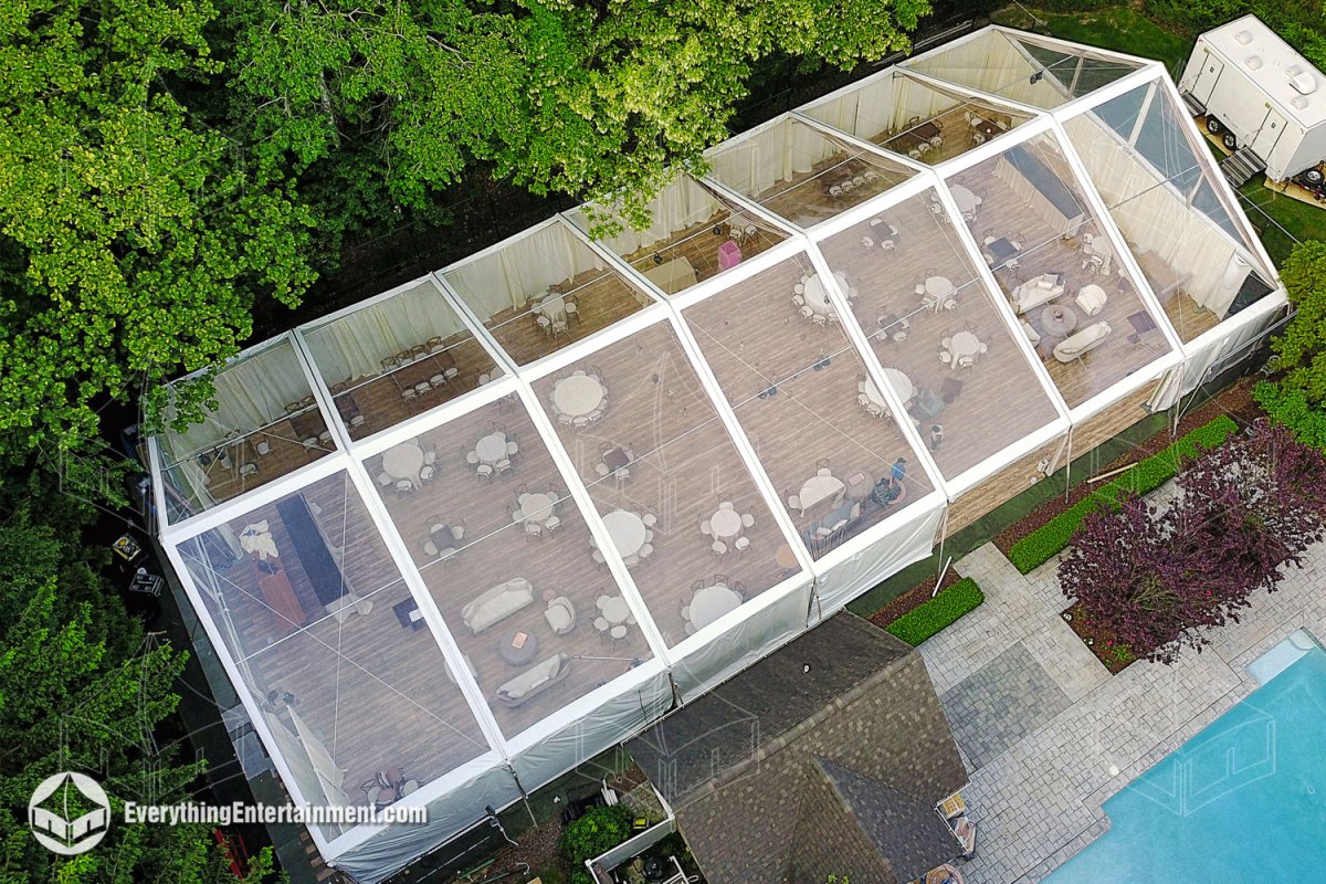 Aerial view of a 50x100 clear top wedding tent with wood plank flooring on a tennis court in Upper Saddle River NJ by Everything Entertainment.