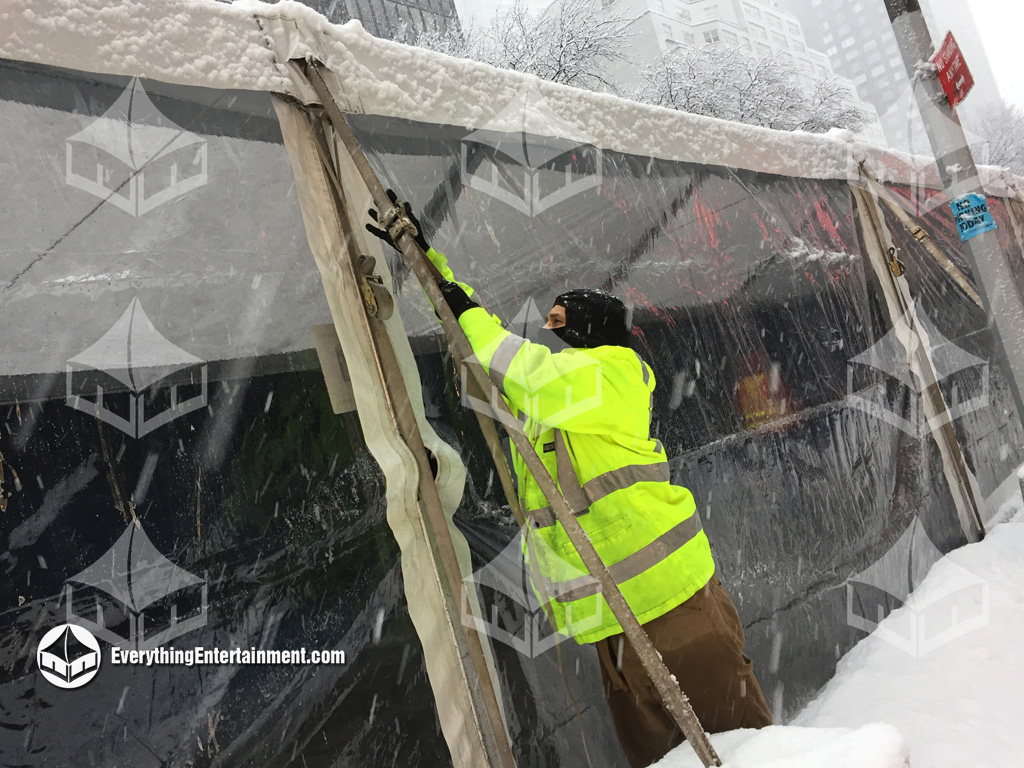 tent installer working on tent rental in a snowstorm