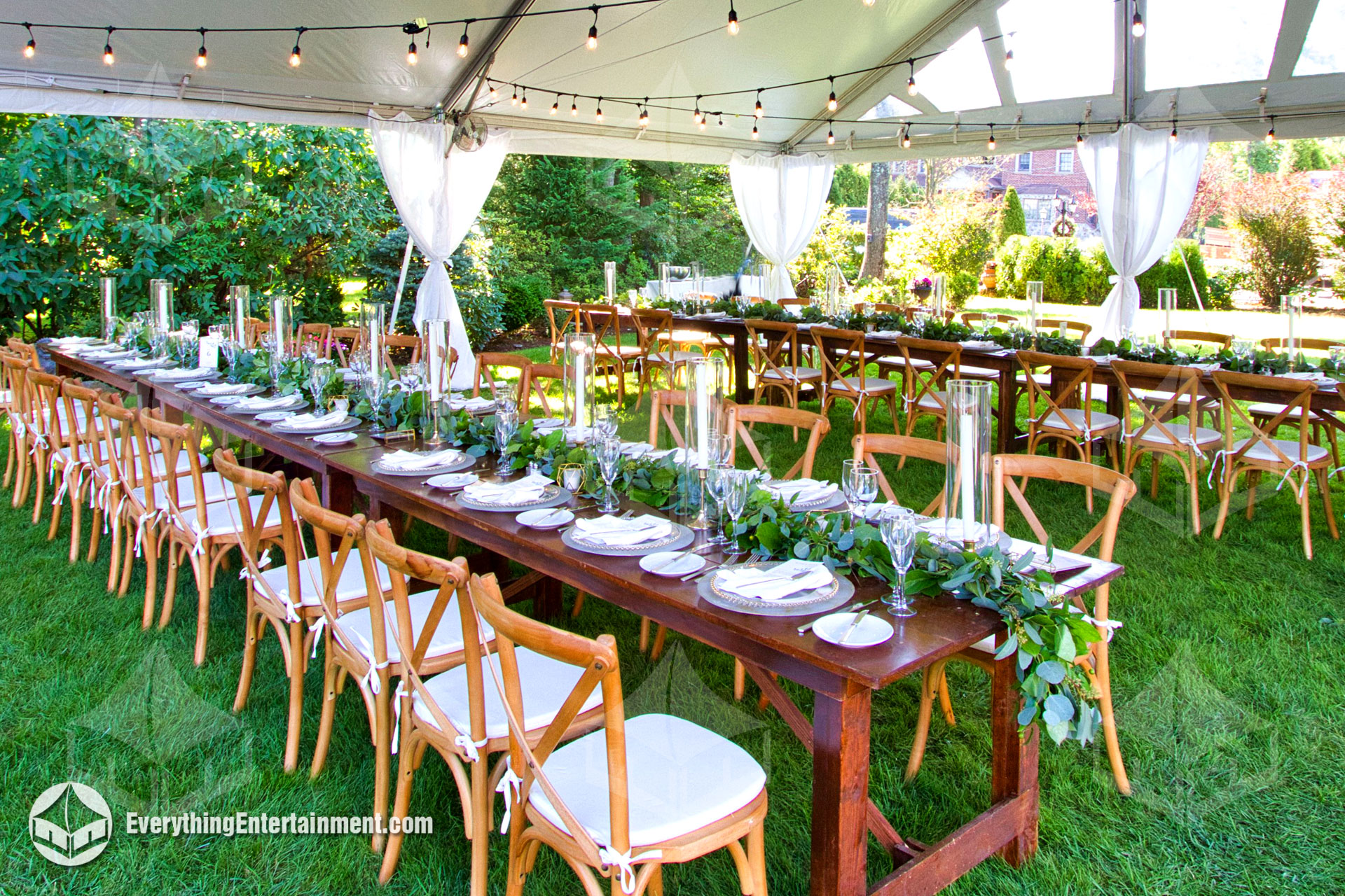 cross back chairs and farm tables setup underneath a large party tent