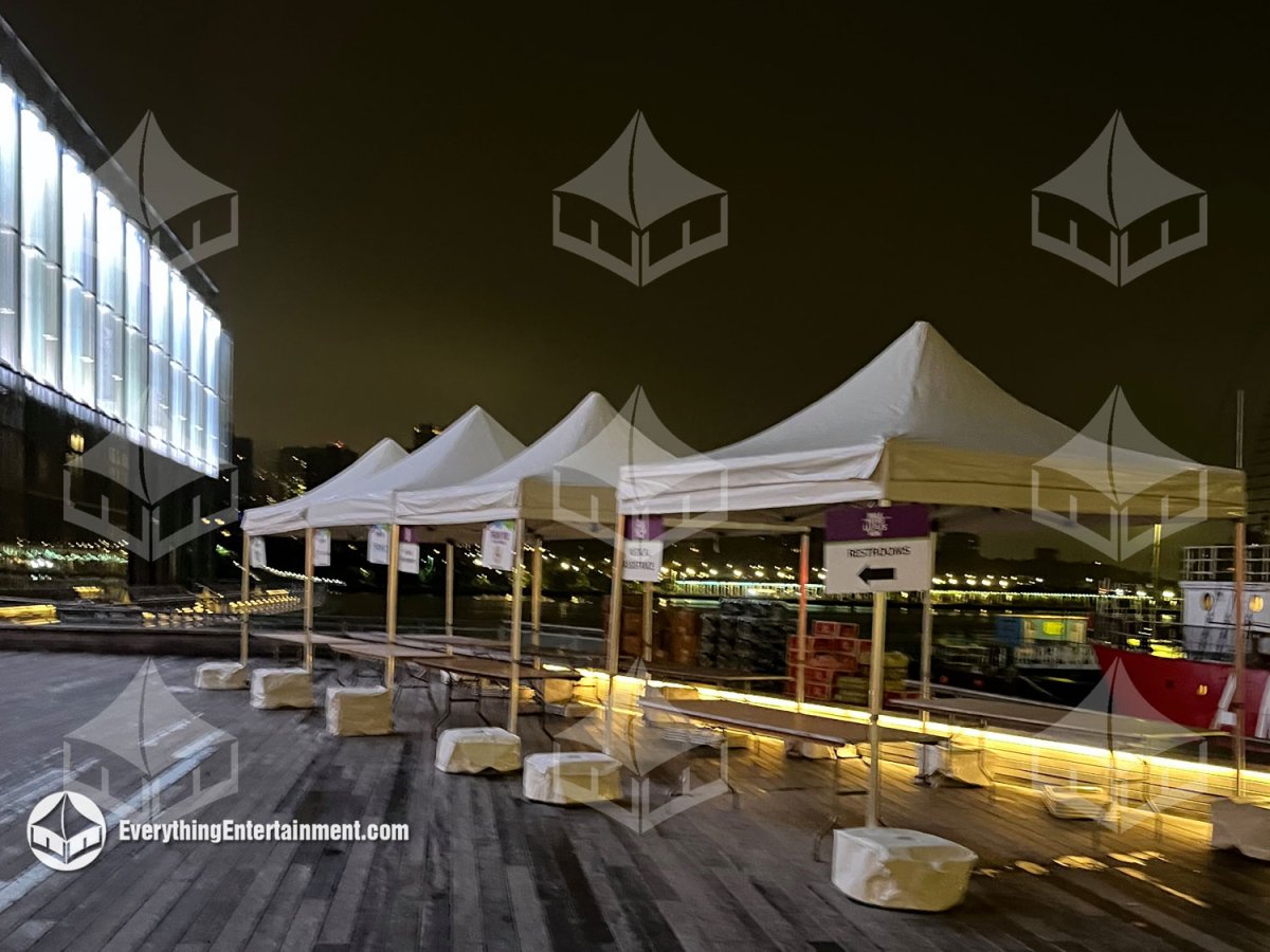 Line of white 10x10 frame tents with registration tables installed on Pier 16 near the historic tall ships in South Street Seaport by Everything Entertainment.