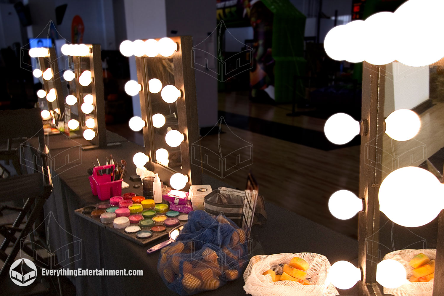 Black framed makeup mirror with bulbs set up with makeup on tables