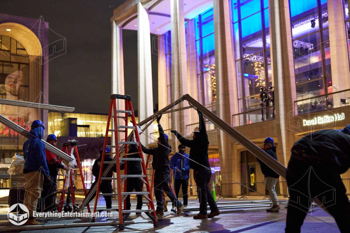 Everything Entertainment crew assembling metal frame tent trusses at night outside David Geffen Hall at Lincoln Center.