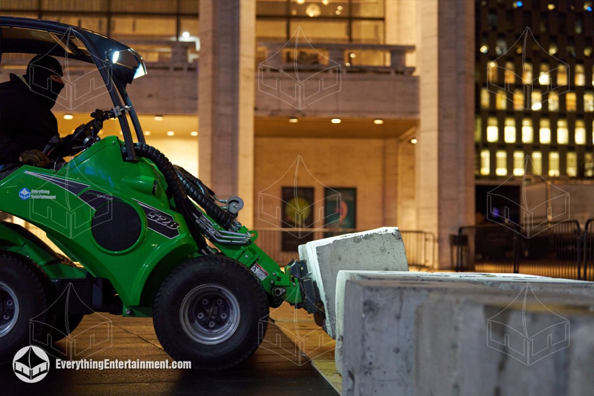 Heavy machinery moving concrete ballast blocks for a major movie premiere tent installation at Lincoln Center.