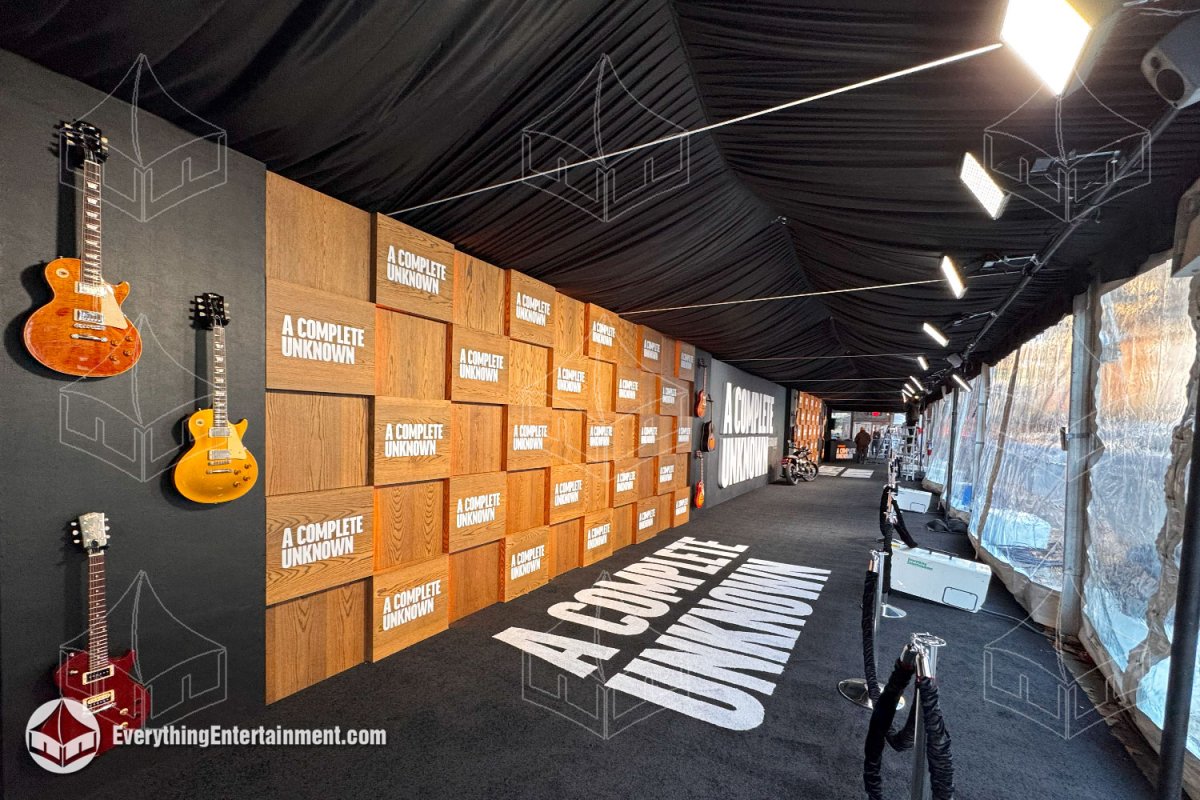 Interior of a 15x125 movie premiere tent featuring a black ceiling liner, custom lighting rigging, subfloor, and wood-paneled press backdrop at SVA Theatre in NYC.