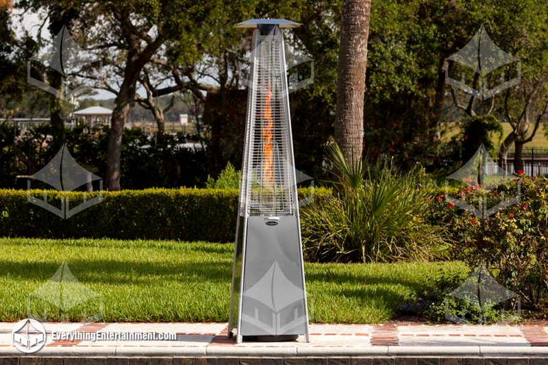 Patio glass tube heater setup in backyard with bushes and trees in background