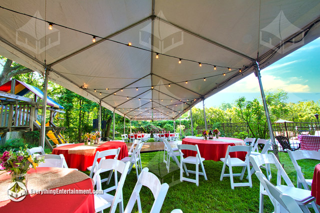 Interior of a party tent with tables, chairs, and bistro string lights.