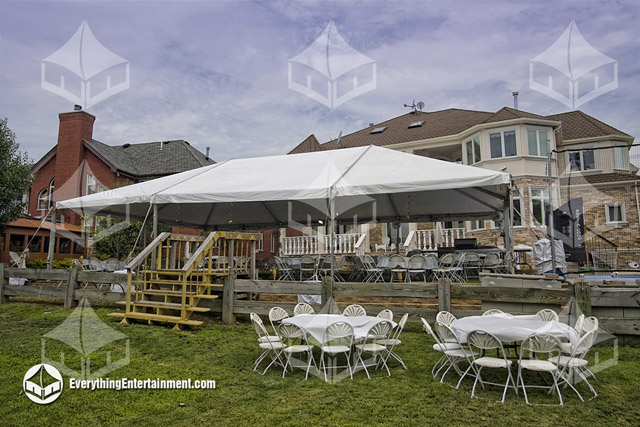 A tent setup in a backyard for a party with a large house in the background