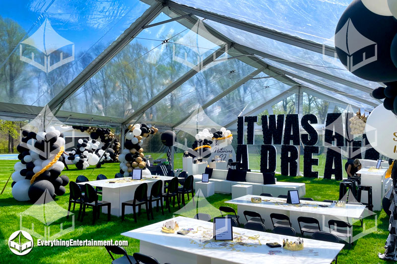 30x50 foot clear top tent setup with black, white decorations, including gold accents, on grass