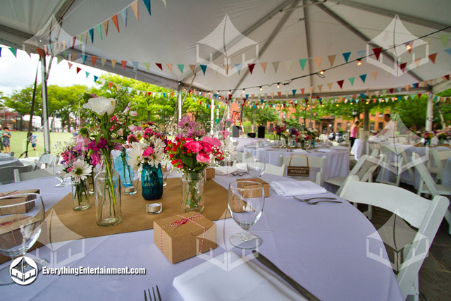 Interior view of a wedding tent with spring decor and decorative pennant flags.