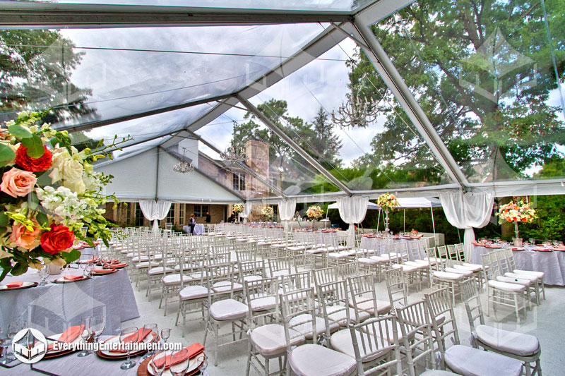 A large clear top wedding tent with white carpet setup in a New Jersey Backyard