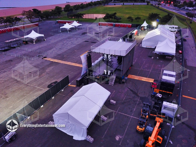 Multiple tents for a concert setup on a huge asphalt parking lot.