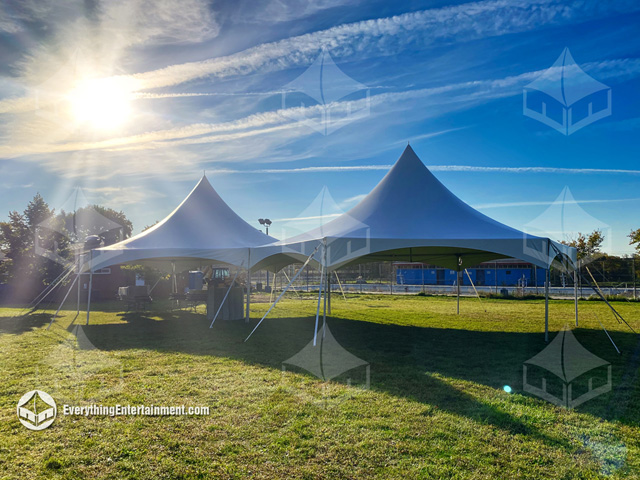 Two high-peak tents setup on grass with a beautiful sunburst