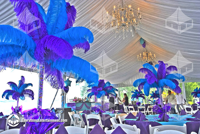 The interior of a 30x60 Party Tent with a white fabric liner, chandeliers, and colorful feather centerpieces.