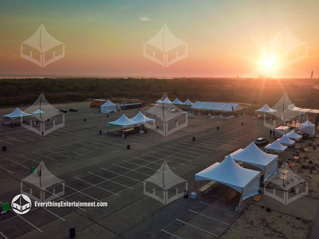 Many tents setup for a charity walk at sunrise on a large parking lot.