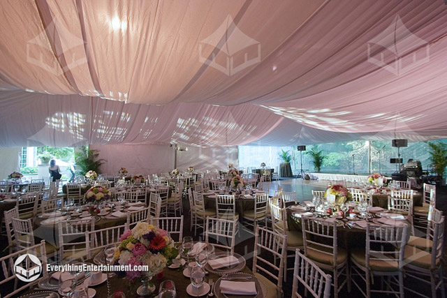 The interior of a 40x80 frame tent with a fabric liner backlit in pink setup for a NJ backyard wedding