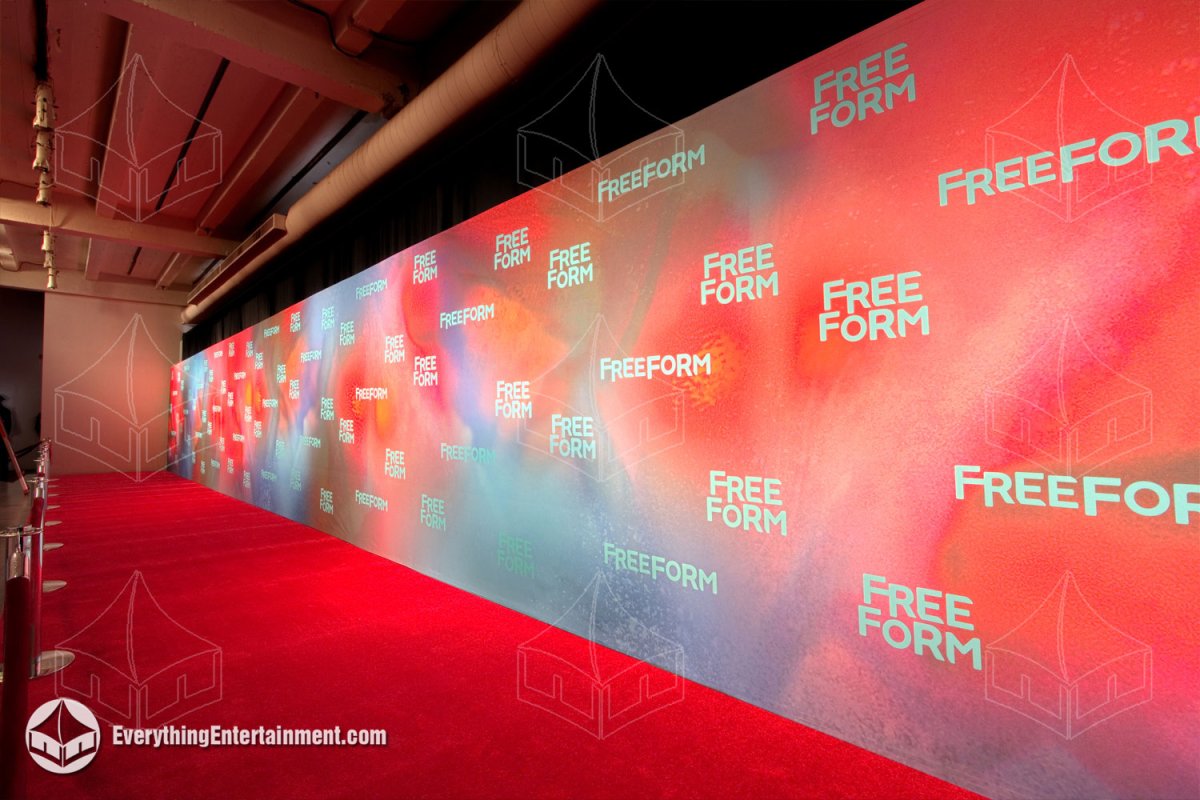 Vibrant red Freeform upfronts step and repeat media wall with matching red carpet runner and overhead event lighting installed in NYC by Everything Entertainment.