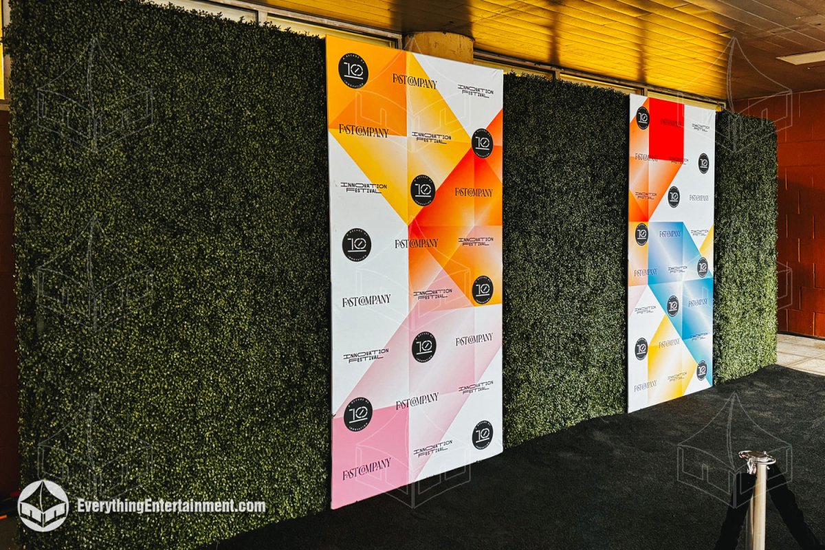 Fast Company branded step and repeat logo panels embedded into a boxwood hedge wall backdrop with black carpet by Everything Entertainment.