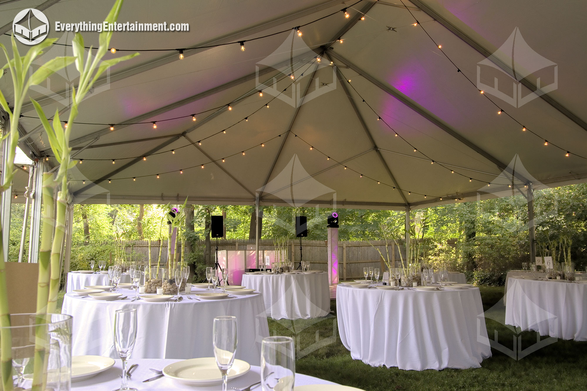 Interior of a frame tent with tables, chairs, and string lights