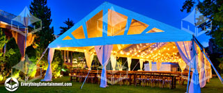 Frame tent with string lights and farm tables with dark blue sky