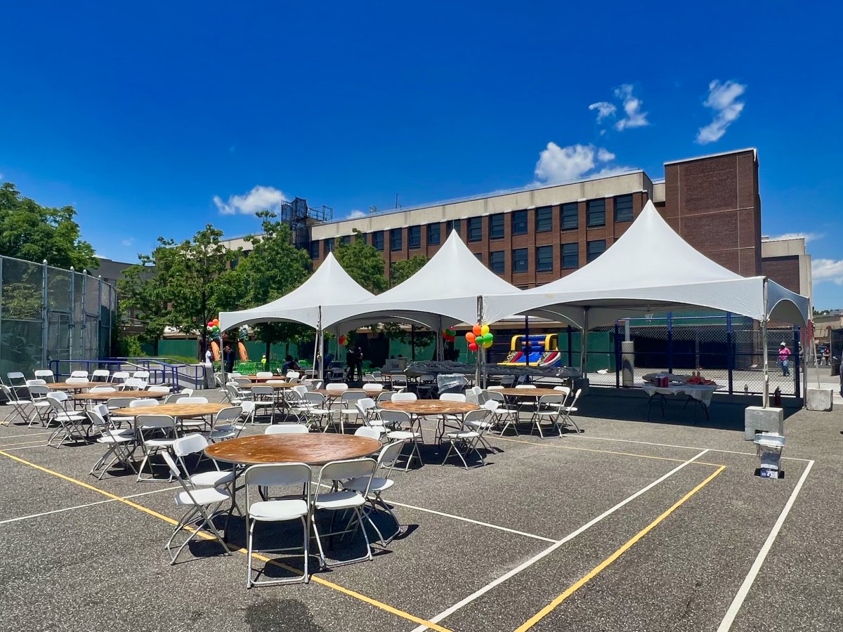 High-peak frame tents with round tables and folding chairs set up on a school outdoor court for a graduation reception by Everything Entertainment.